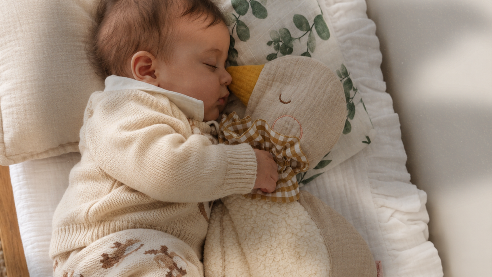 Bebê aconchegado com naninha de tecido e peças delicadas para presentear.